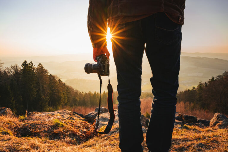 photographer with camera in sunset taking photos of landscape t