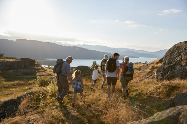 rear view of multi generation family walking on top of hill on hike through countryside in lake district uk